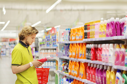 Homme faisant du shopping dans un supermarché lisant des informations sur les produits.(couches, détergent)