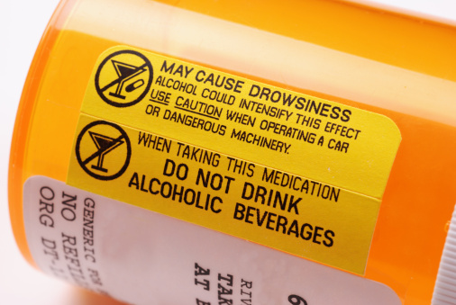 Close-up d'une étiquette sur une bouteille de médicaments sur ordonnance avertissant de ne pas consommer d'alcool lors de l'utilisation de la drogue